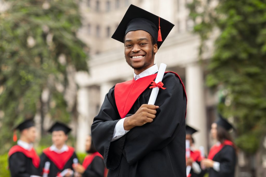 Cheerful african american guy in graduation costume